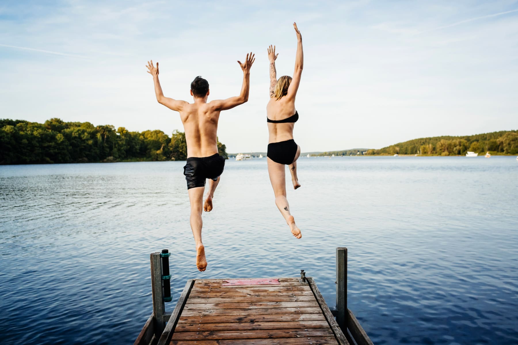 Two people jumping into lake