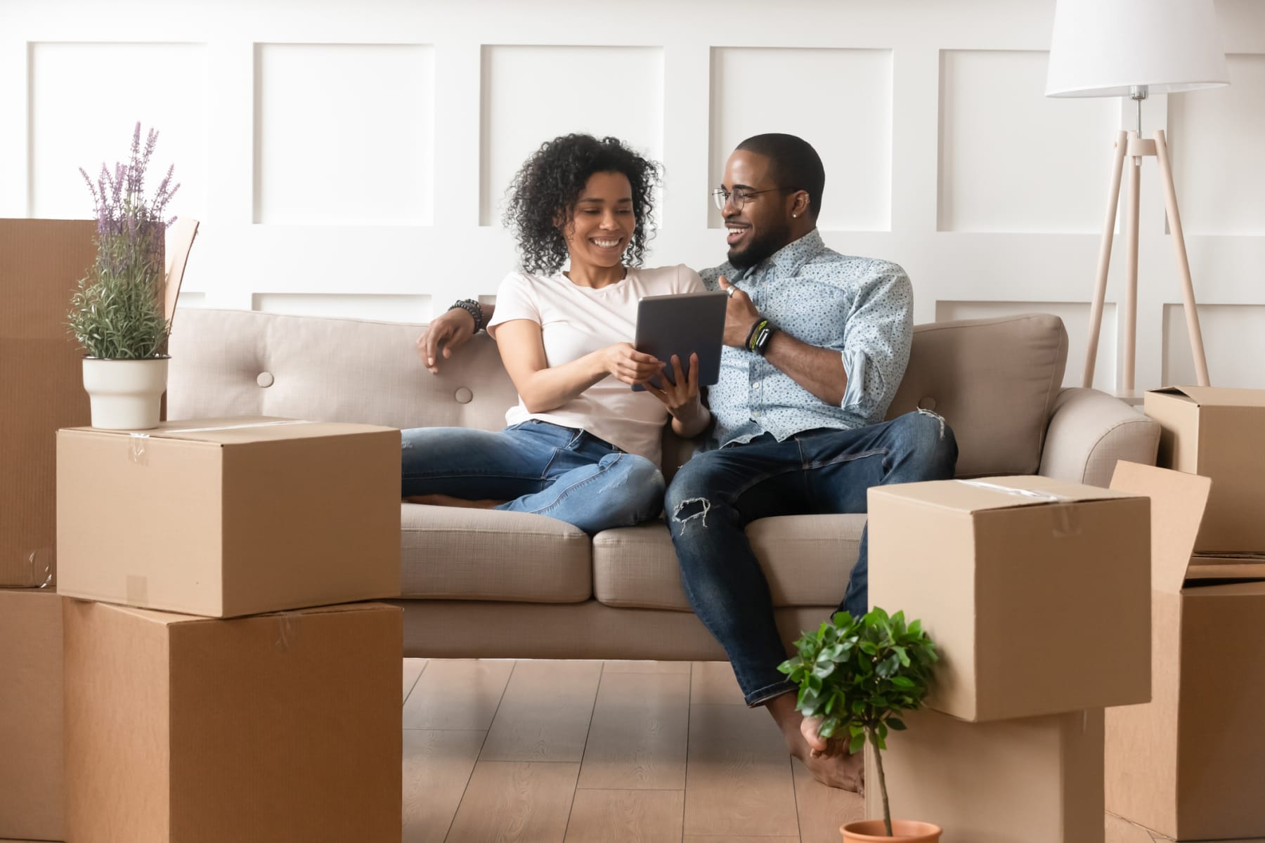 couple sits on couch and looks at tablet