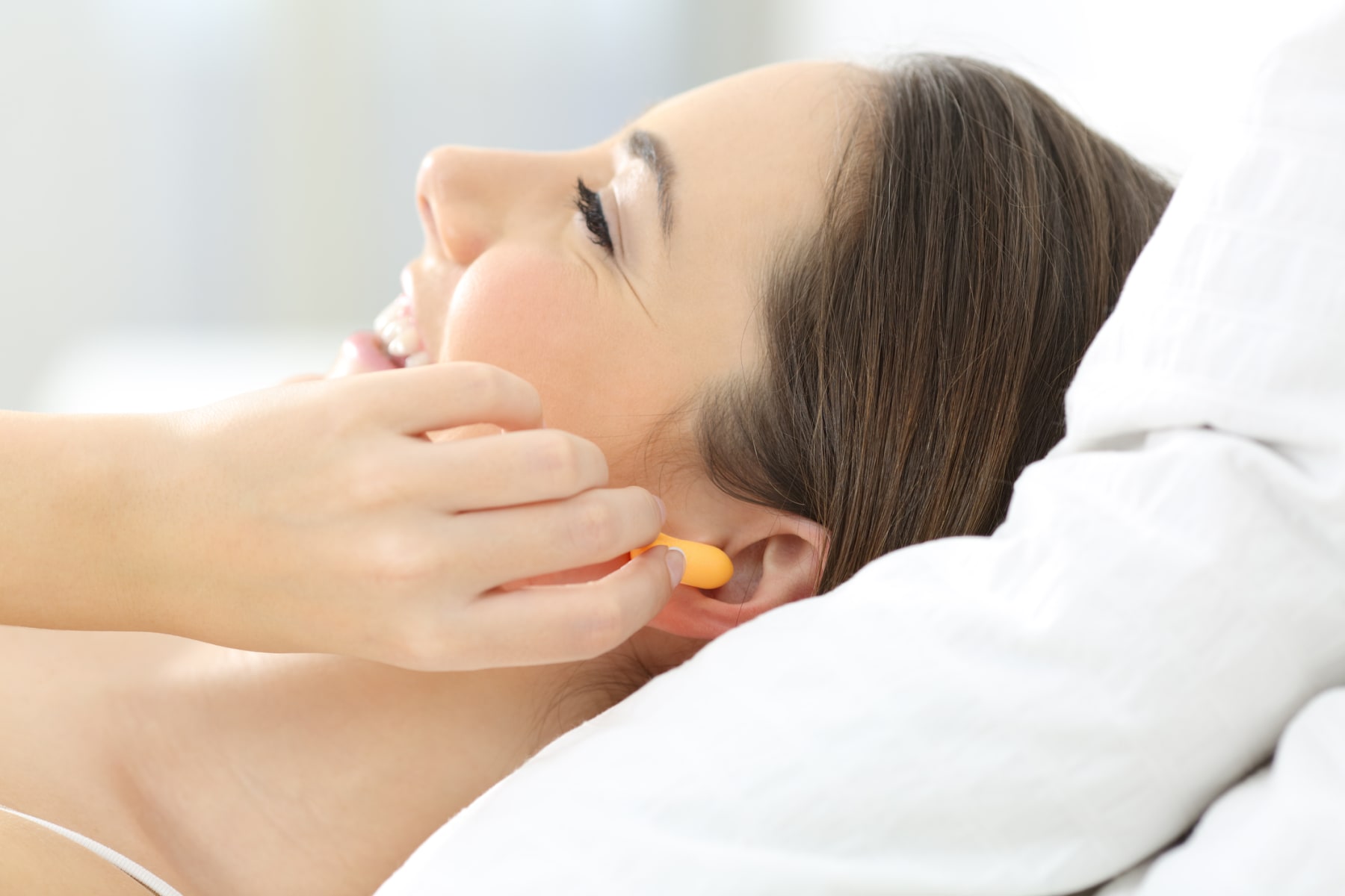 woman uses earplugs in bed