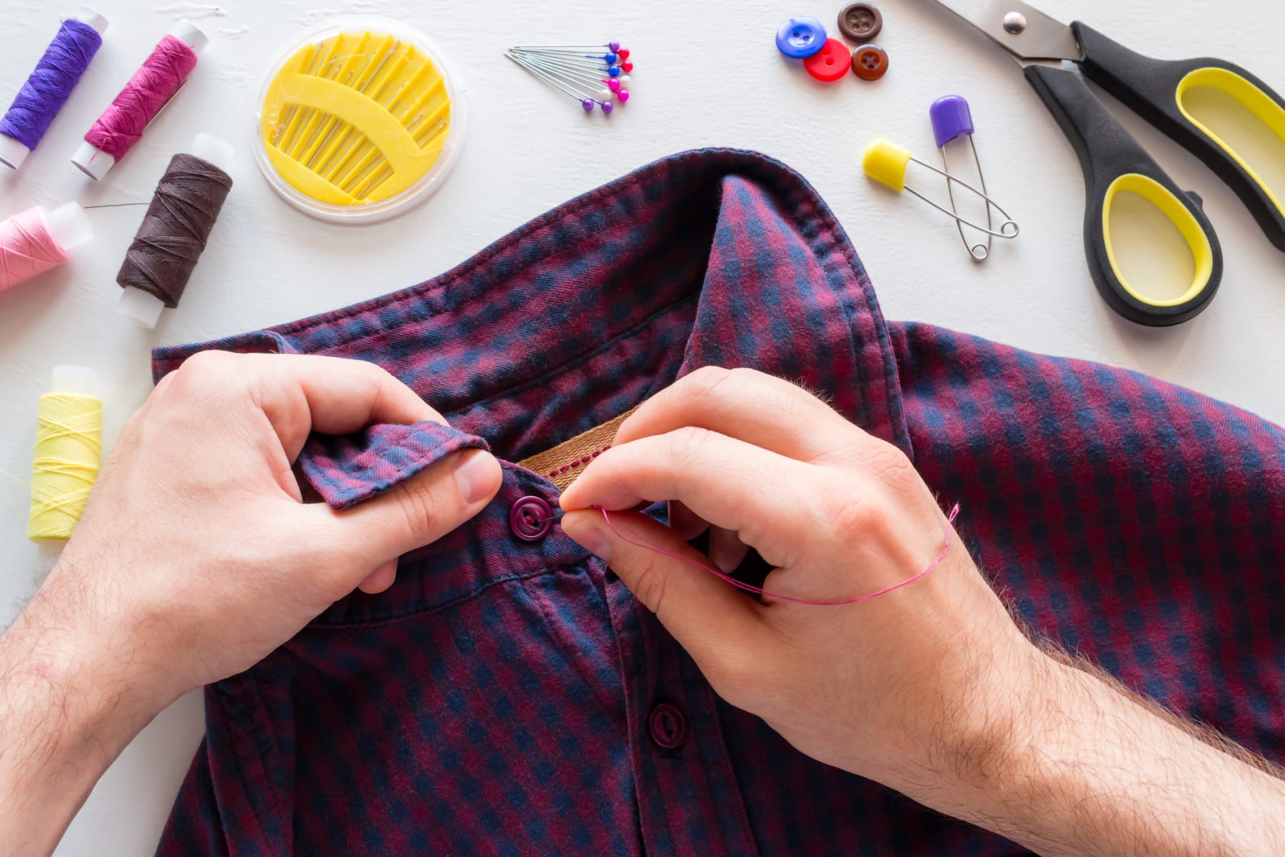 man sews button on shirt
