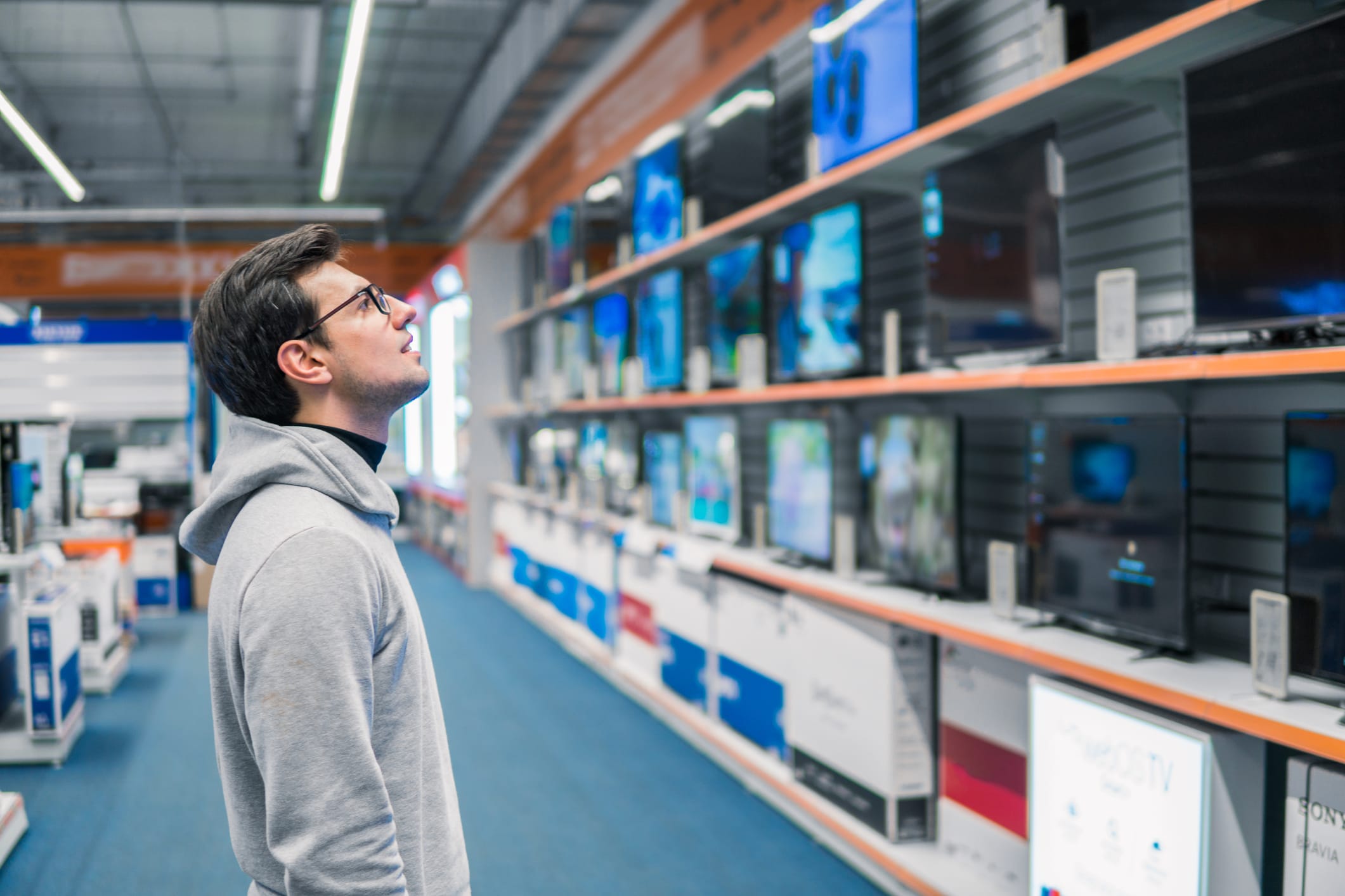 man looking at TVs