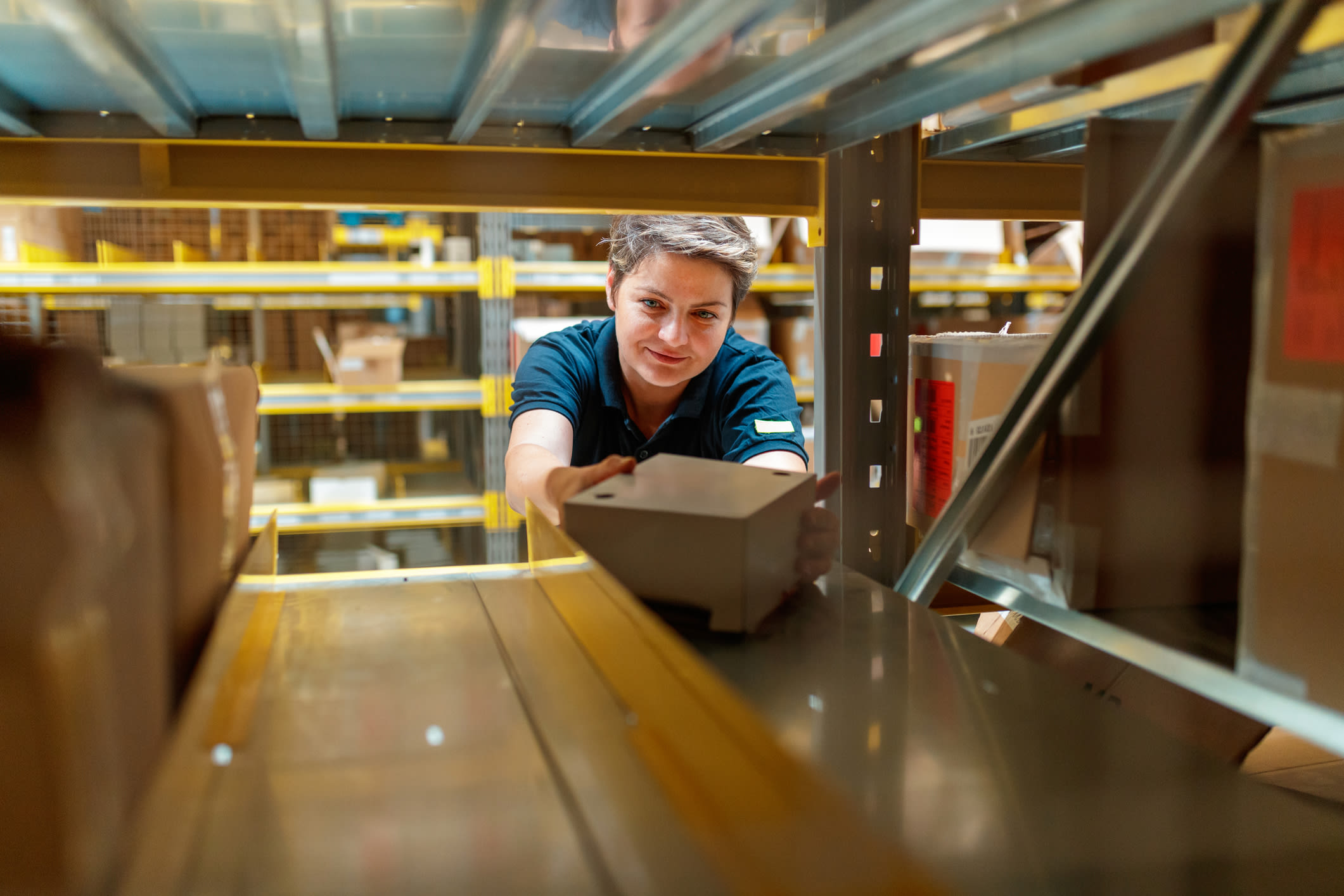 Female Warehouse Worker Grabs Box From Shelf